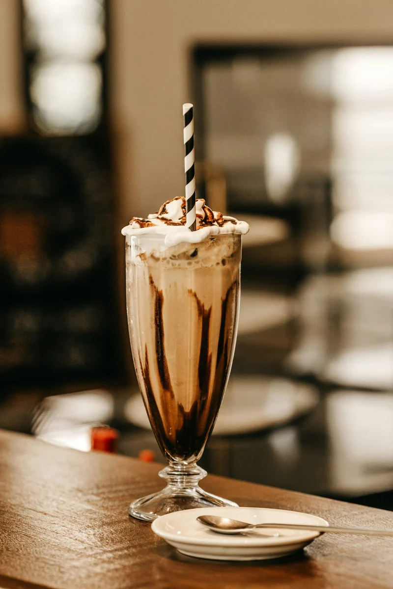 Chocolate milkshake with whipped cream and a striped straw (demo photo)