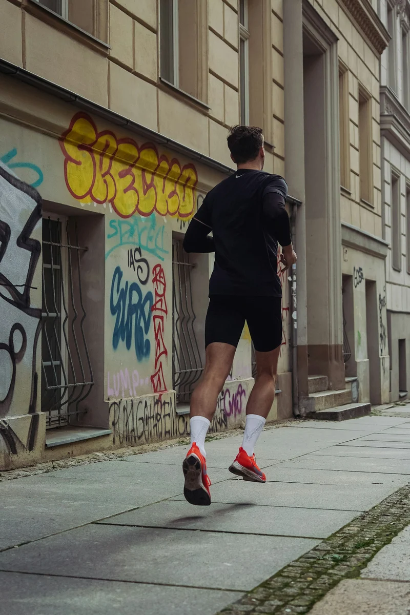 Runner in black shorts and top on a city sidewalk (demo photo)