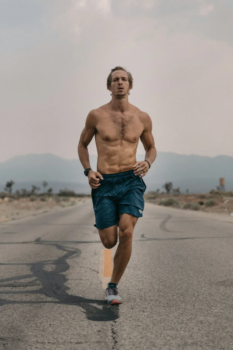 Runner in dark running shorts on an open road (demo photo)