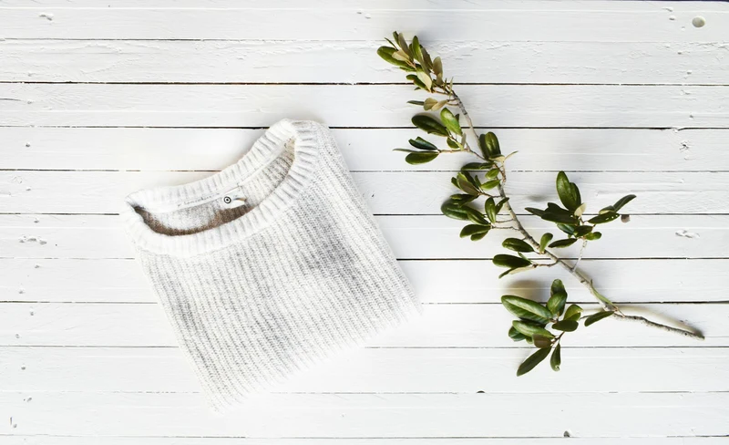 Light knit base layer laid flat on a white wooden surface (demo photo)