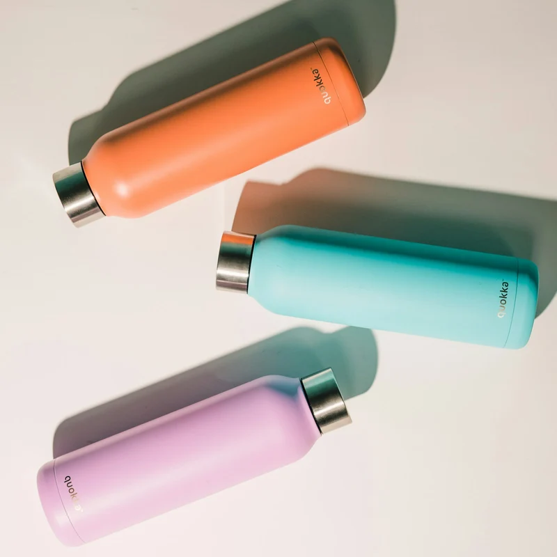 Three insulated metal bottles in orange, teal and pink on a white surface (demo photo)