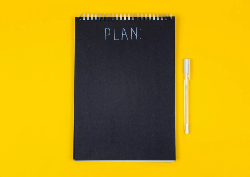 Black planner notebook with the word PLAN on a yellow background (demo photo)