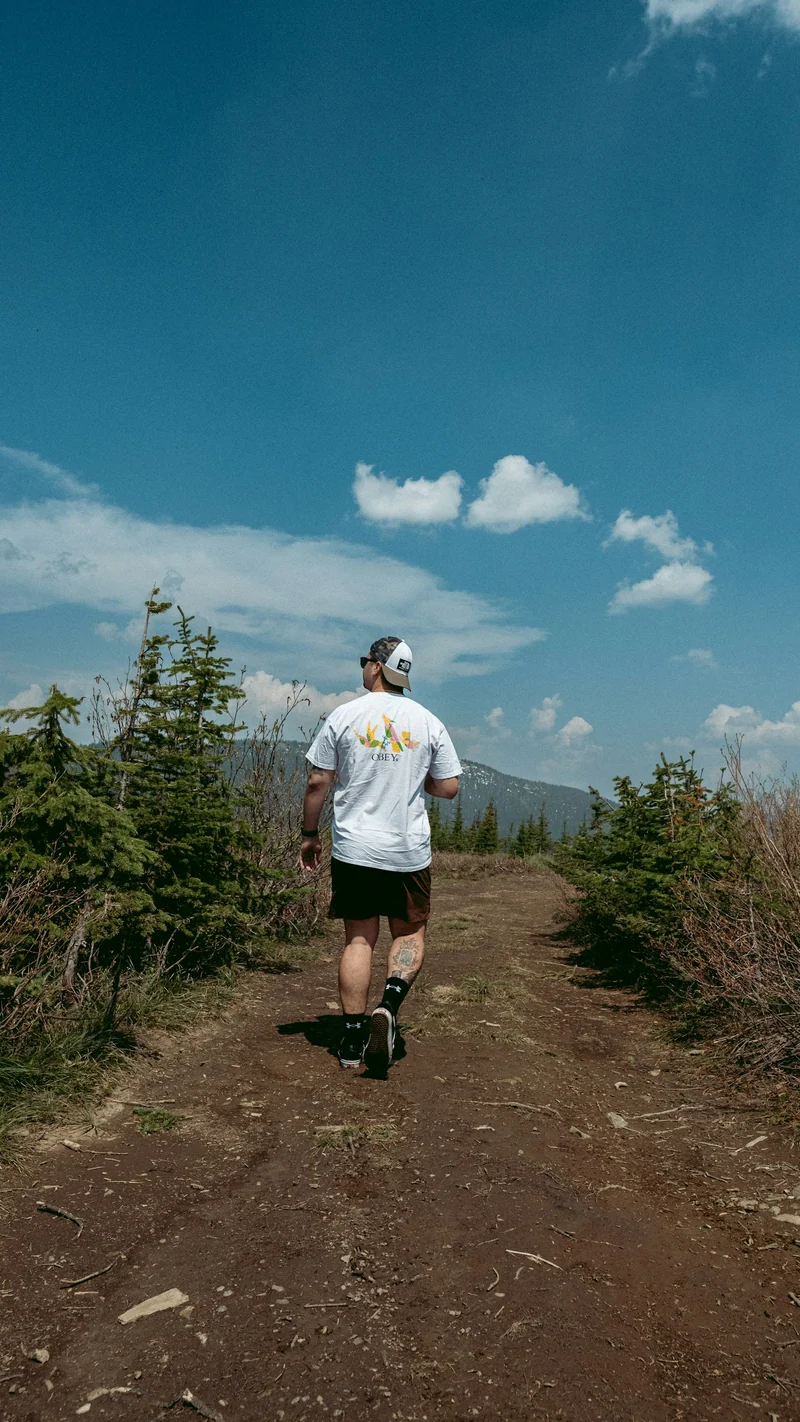 Runner in a light tee on a dirt path with a blue sky (demo photo)